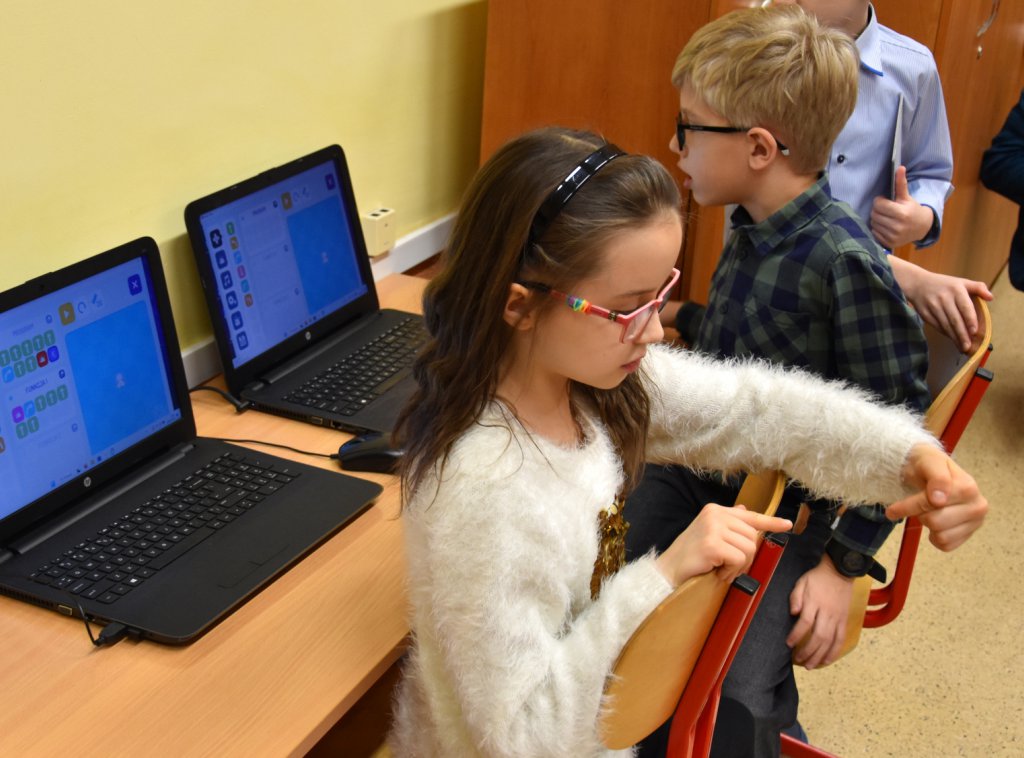 uczniowie klasy 2 siedzą przy komputerze i programują robota